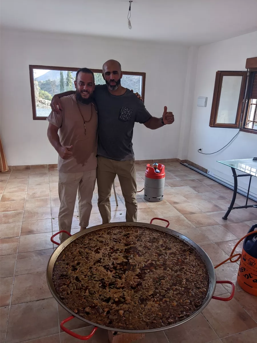 Dos cocineros posan junto a una paella grande recién hecha
