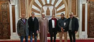 Seis hombres posando ante el mihrab de mármol y madera tallada de la sala de oración