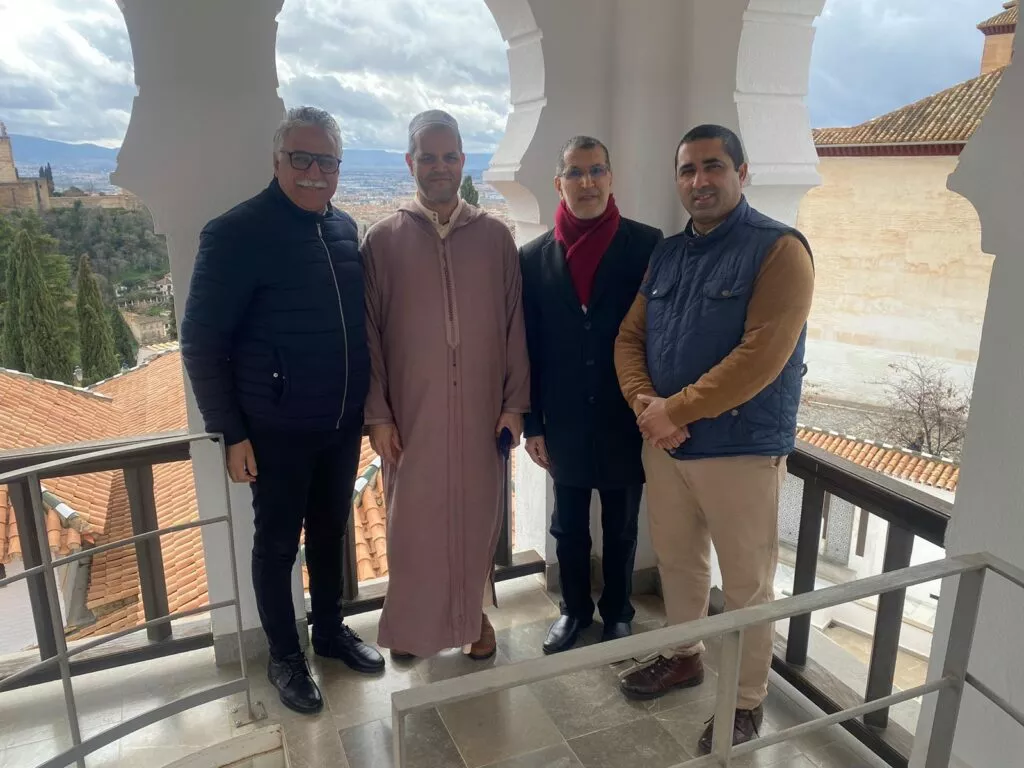 Cuatro personas posan bajo los arcos del mirador de la mezquita, con la Alhambra y la ciudad al fondo