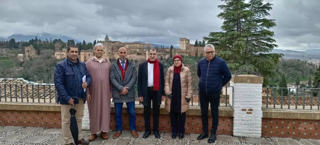 Seis personas posan en el mirador ante la balaustrada, con la Alhambra y la sierra al fondo