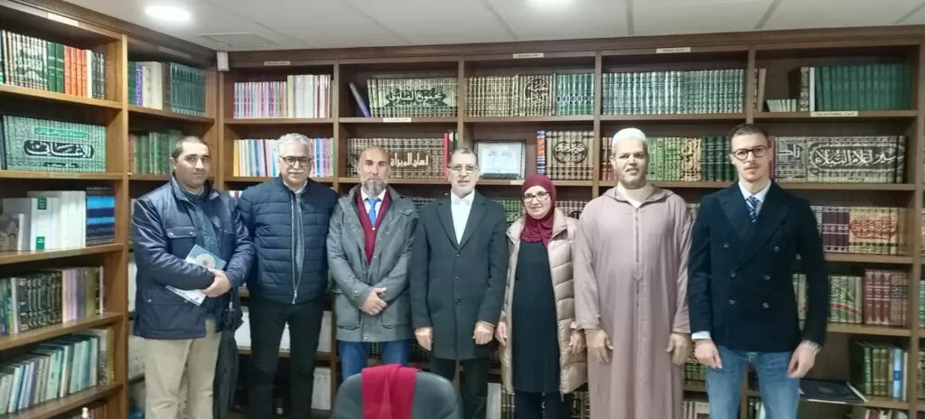 Siete personas posan ante las estanterías de la biblioteca de la mezquita