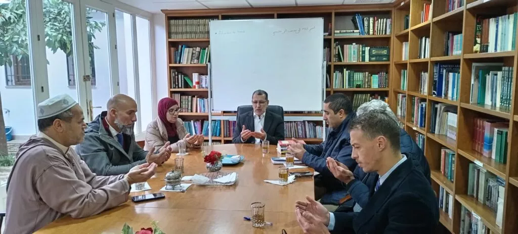 Los asistentes hacen la súplica con las manos abiertas alrededor de la mesa de la biblioteca