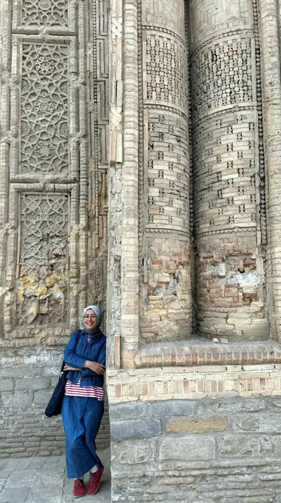 Una asistente al taller posa junto a la portada de ladrillo y yesería labrada de un edificio histórico