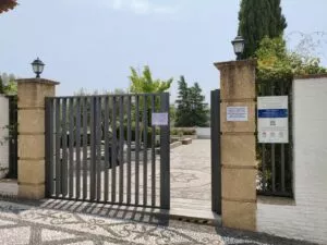 Puerta de reja de la mezquita abierta al patio, con carteles de horario y de cierre por el Eid