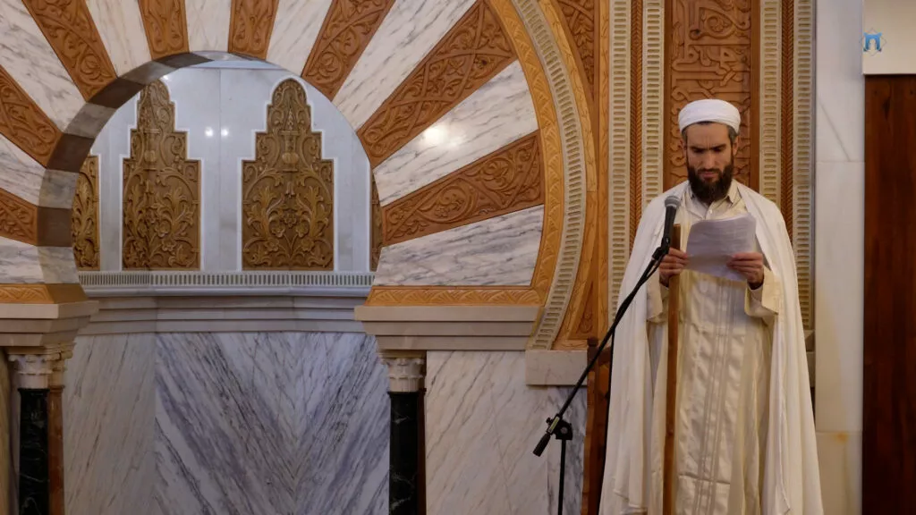 Hafid Malik del Pozo, con turbante y chilaba blancos, lee la jutba ante el micrófono