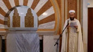 Hafid Malik del Pozo, con turbante y chilaba blancos, lee la jutba ante el micrófono