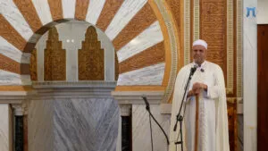 El jatib, en pie junto al mimbar con dos micrófonos delante, se dirige a los fieles