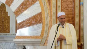 Jatib con chilaba de rayas amarillas y turbante blanco, con las manos sobre el bastón